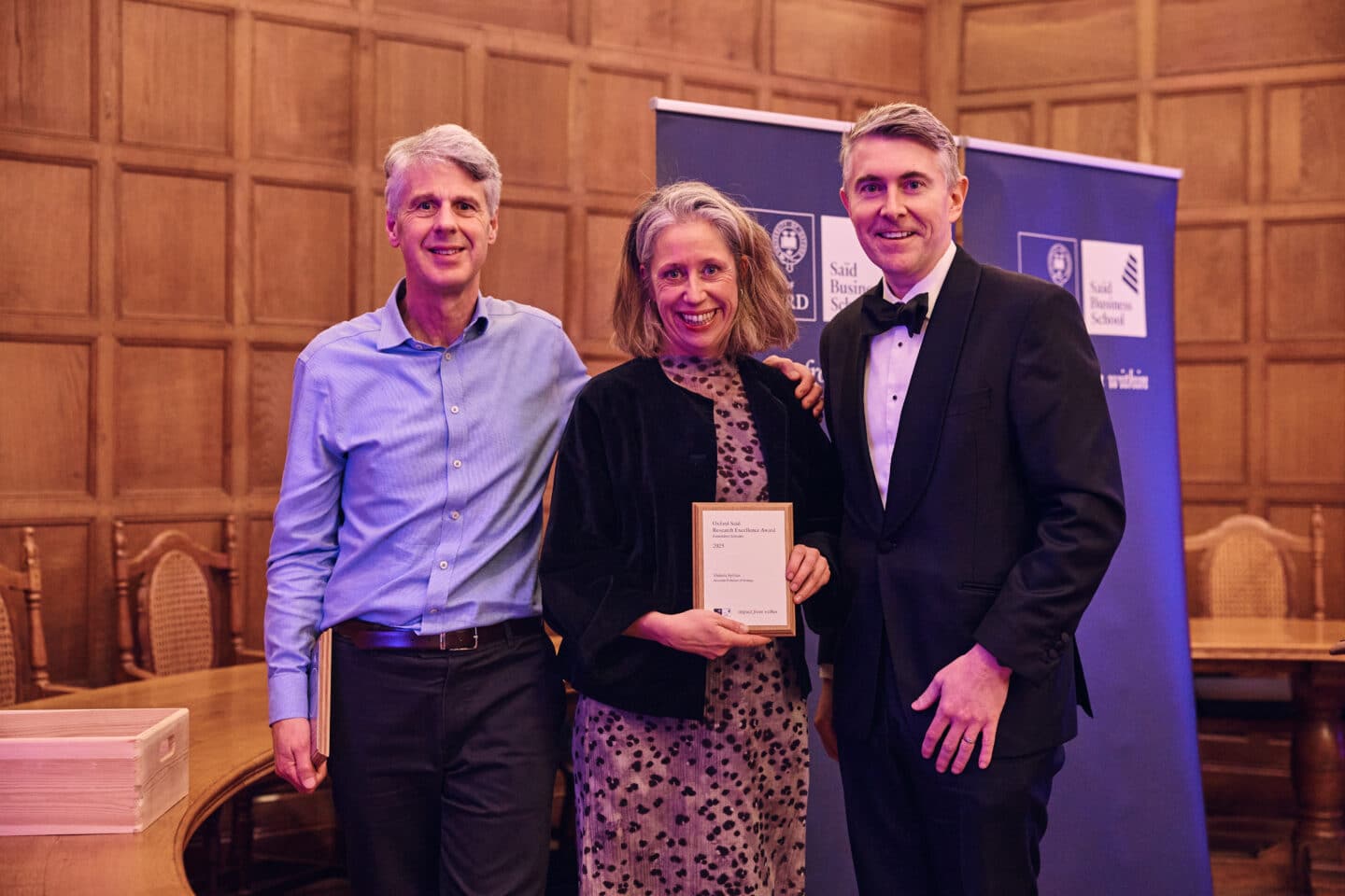 Two men and a woman standing and holding an award.