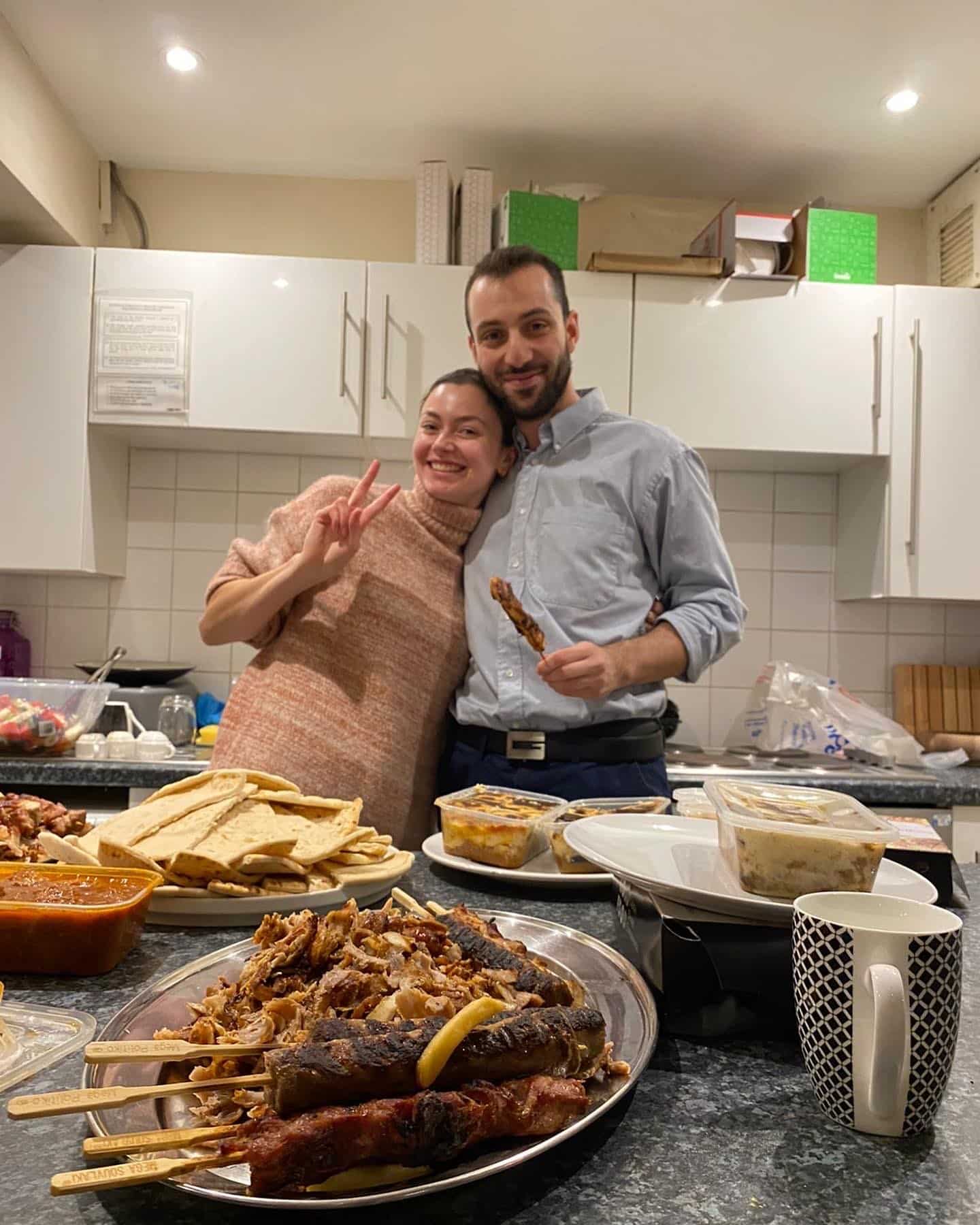 Two people in a kitchen with platters of food