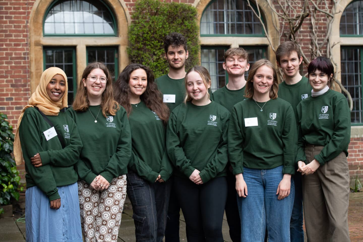 A group of nine people standing outside of a college building