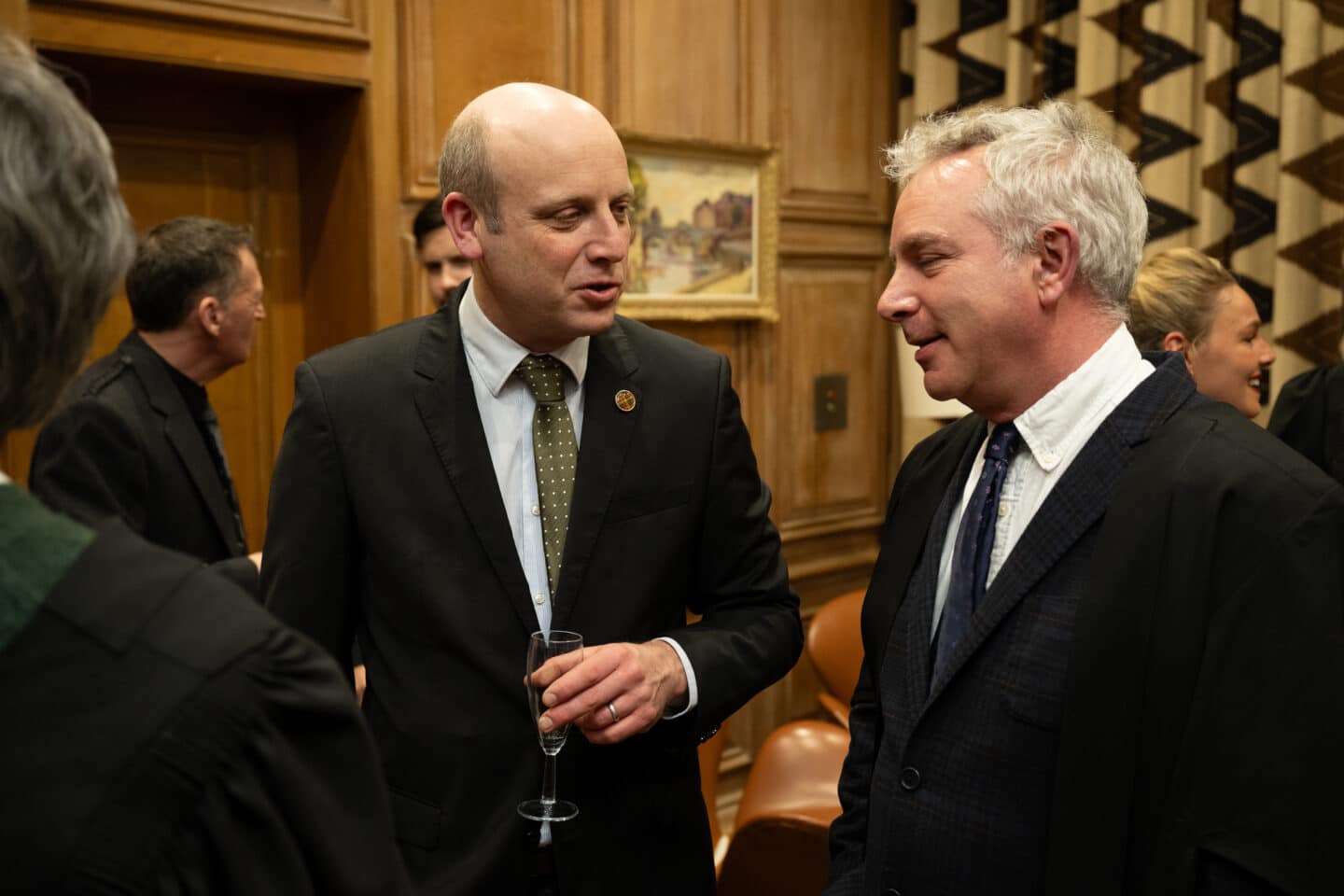 Two men standing indoors and chatting