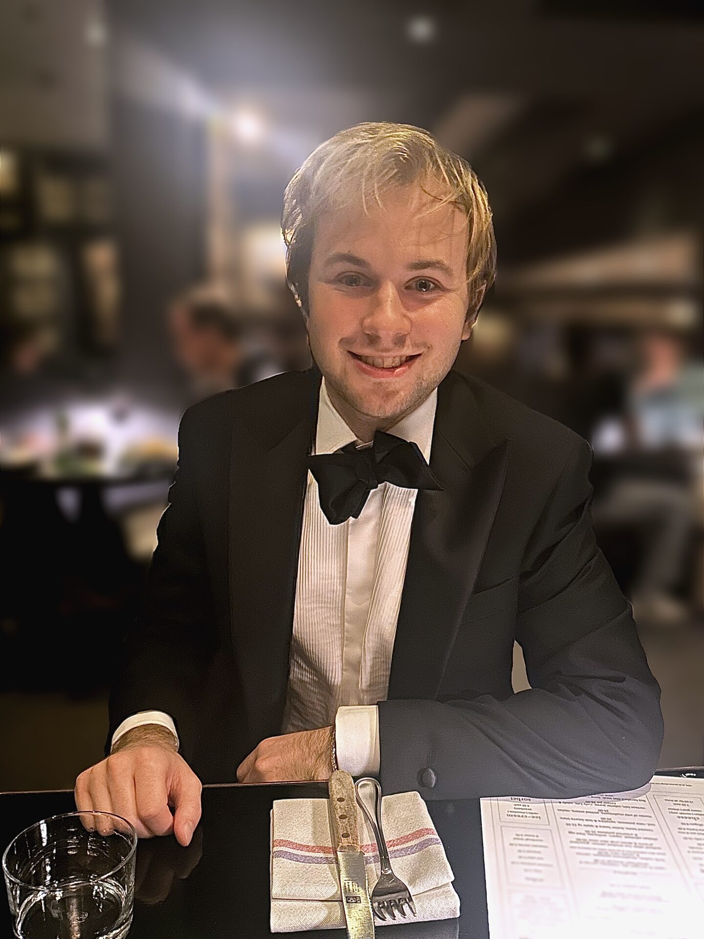 A smiling seated student in black tie