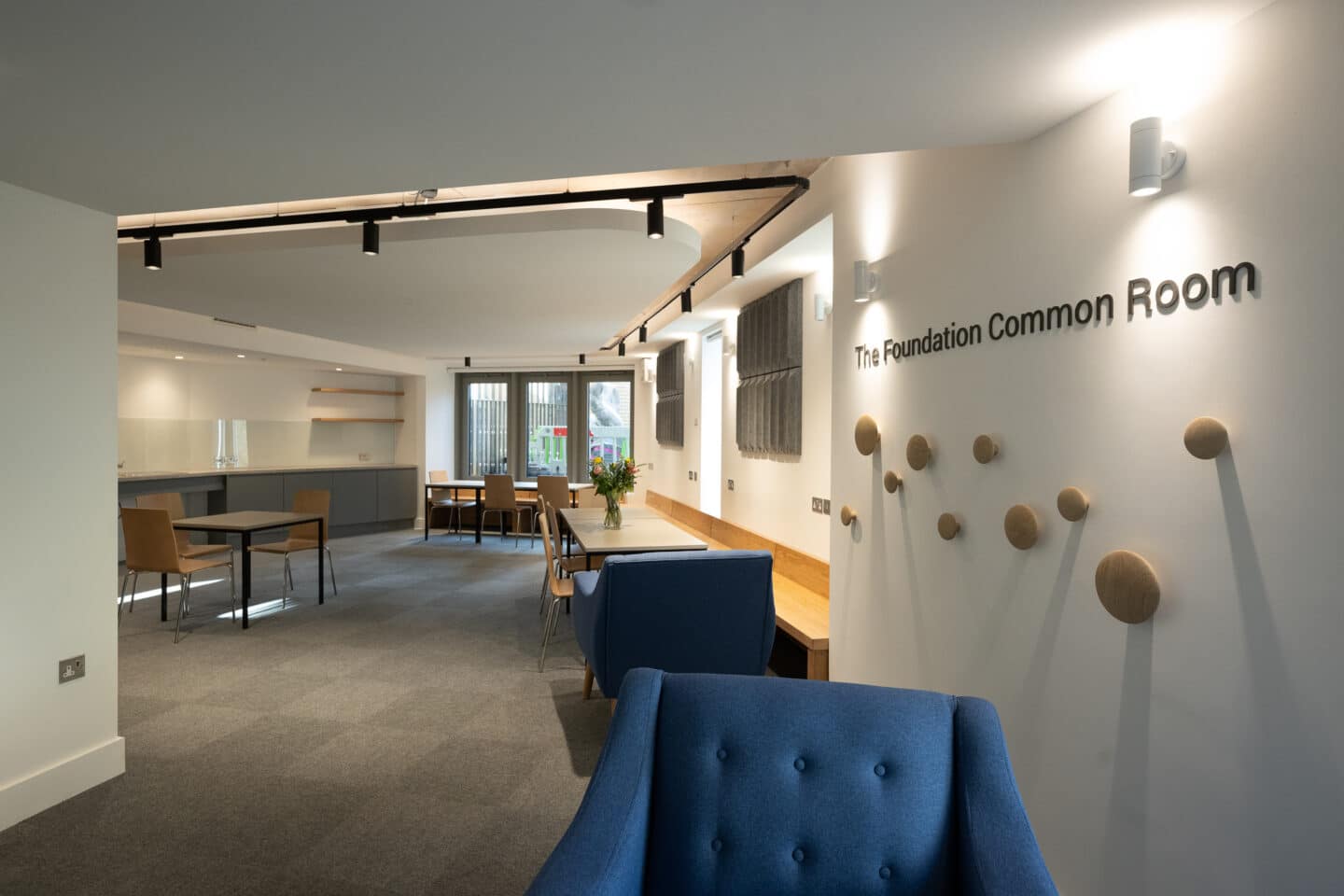 A large common room with soft furnishings, tables and chairs