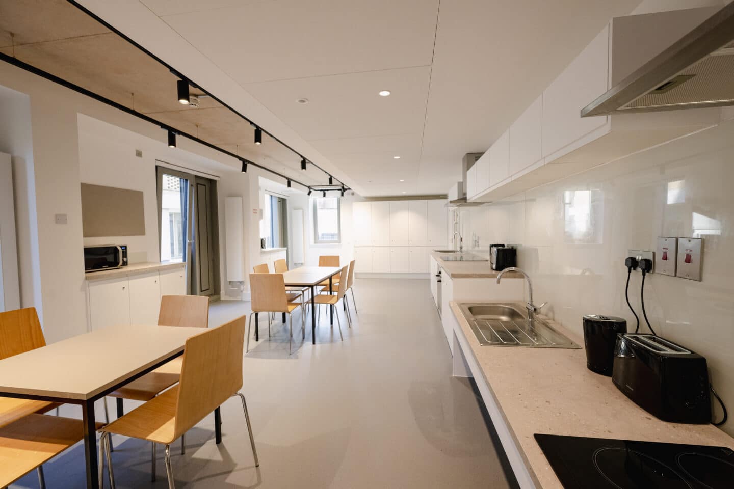 A large communal kitchen with appliances, tables and chairs