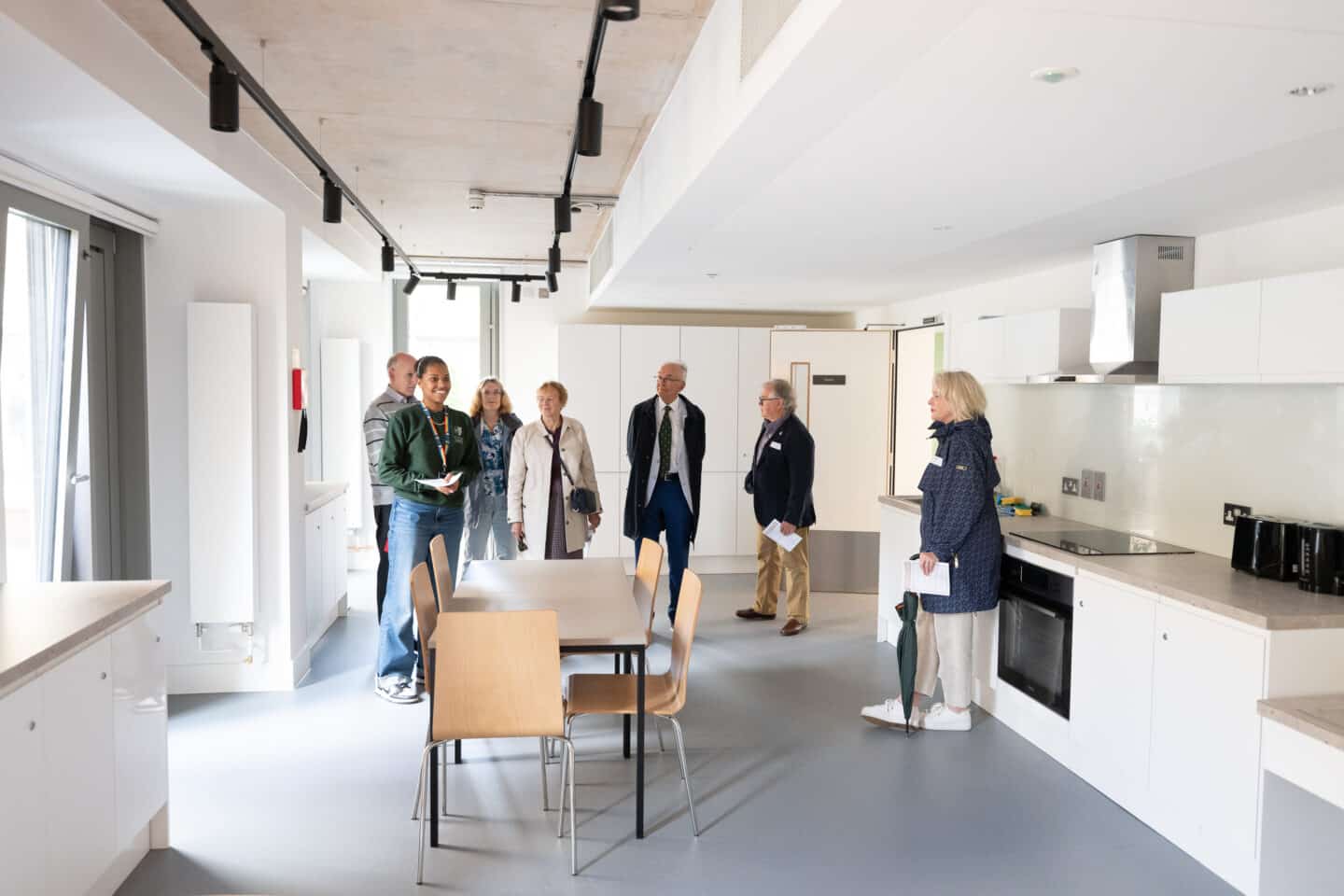 a group of seven people in a large shared kitchen.