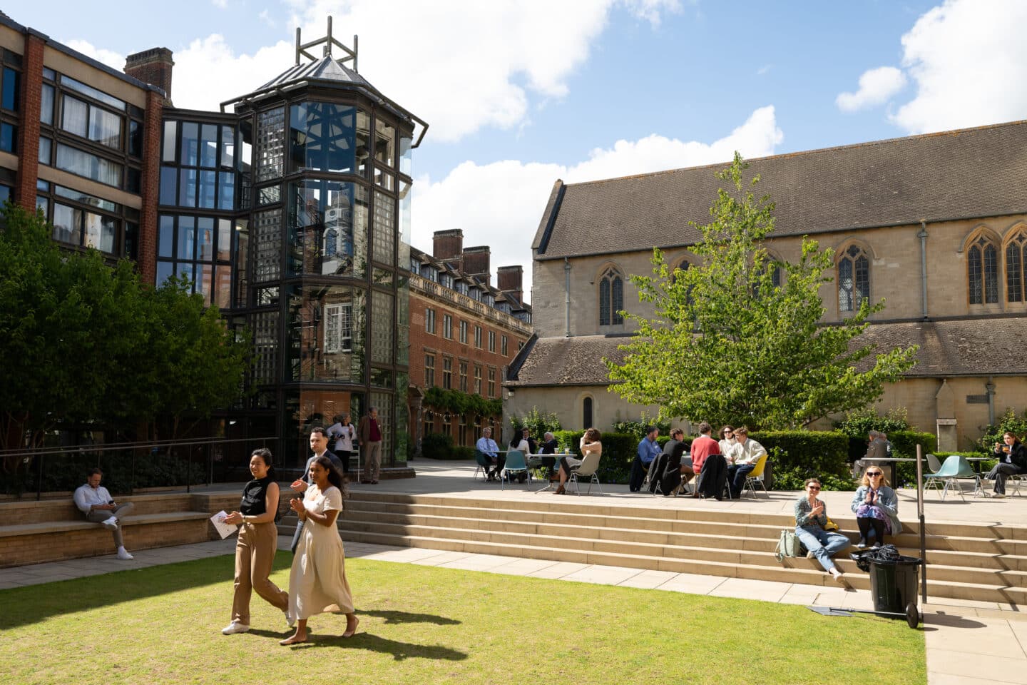 A sunlit college quad with people seated and standing