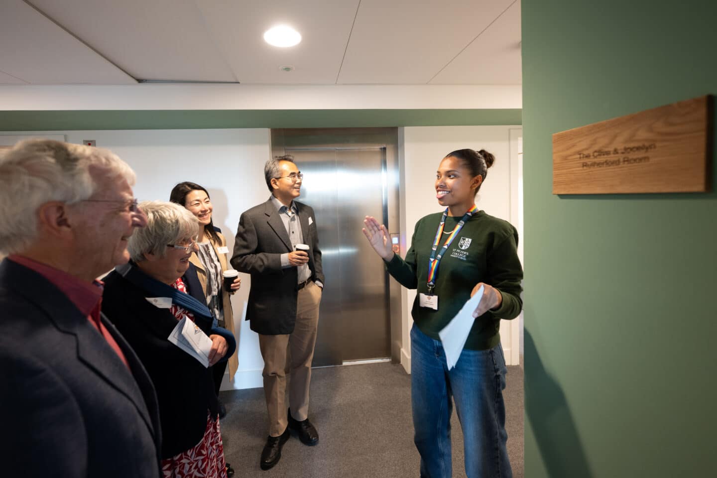 four adults listening to a tour guide in the hallway of a building