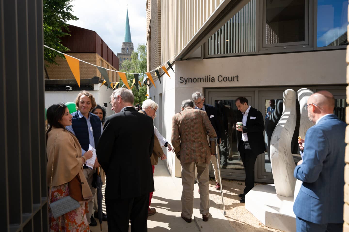 A large group of adults standing near a marble sculpture and mingling