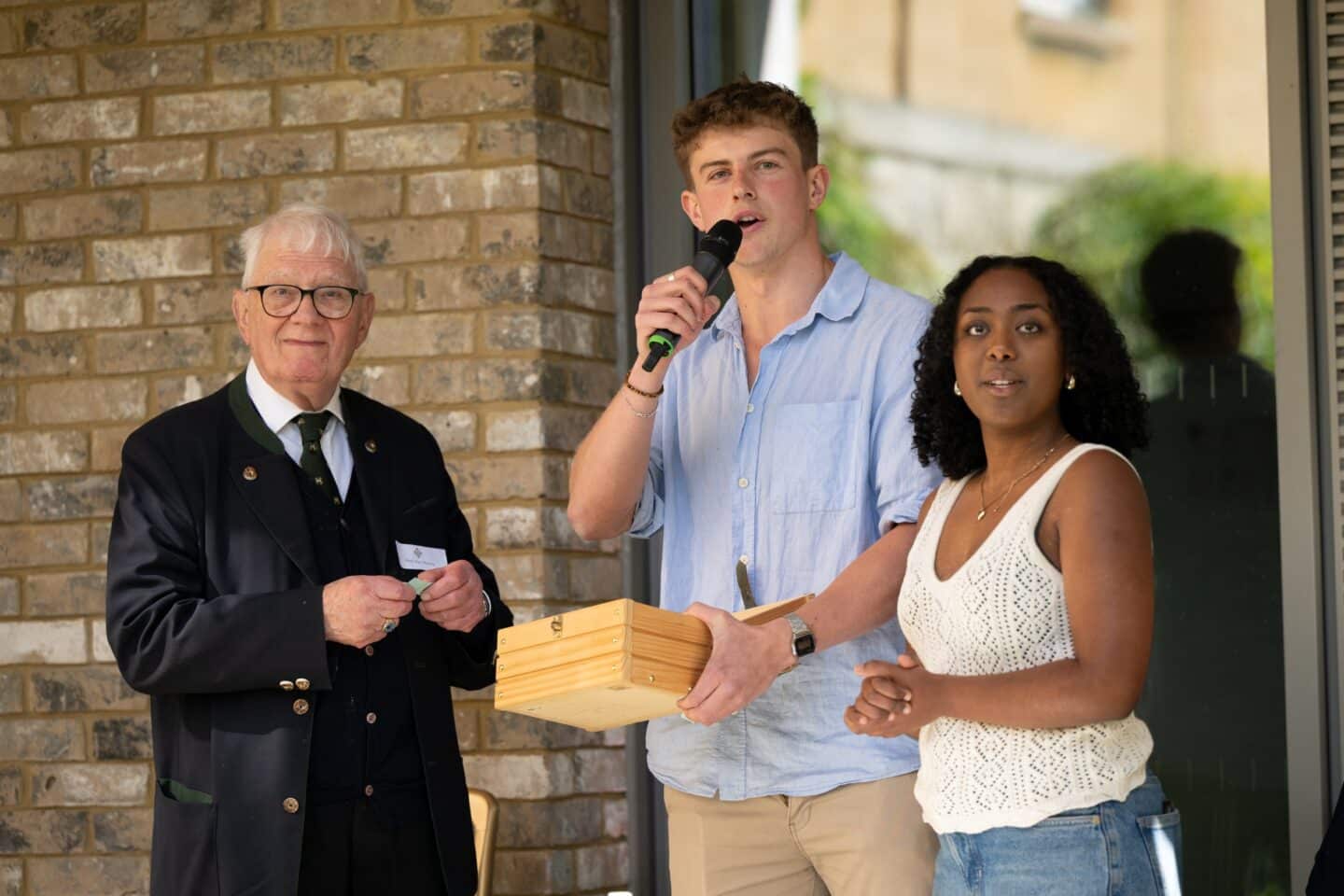 Three adults holding a box and selecting raffle tickets.