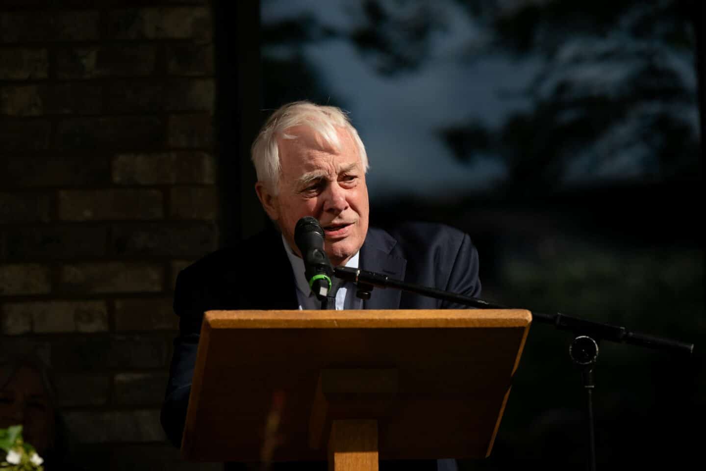 A man standing on an outdoor stage and speaking into a microphone