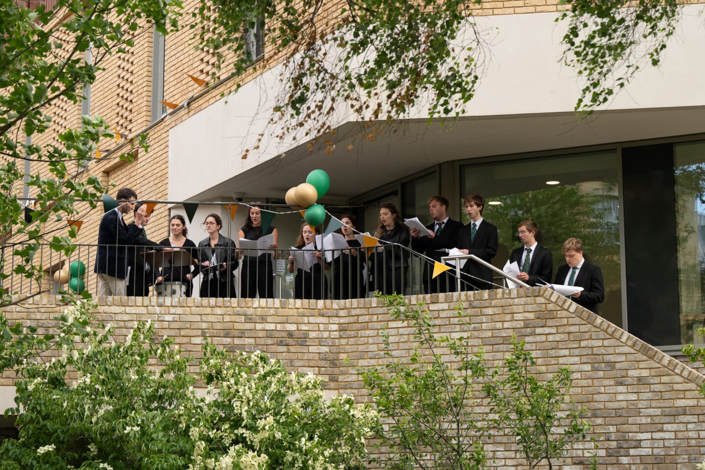 A small choir singing outdoors on a raised platform