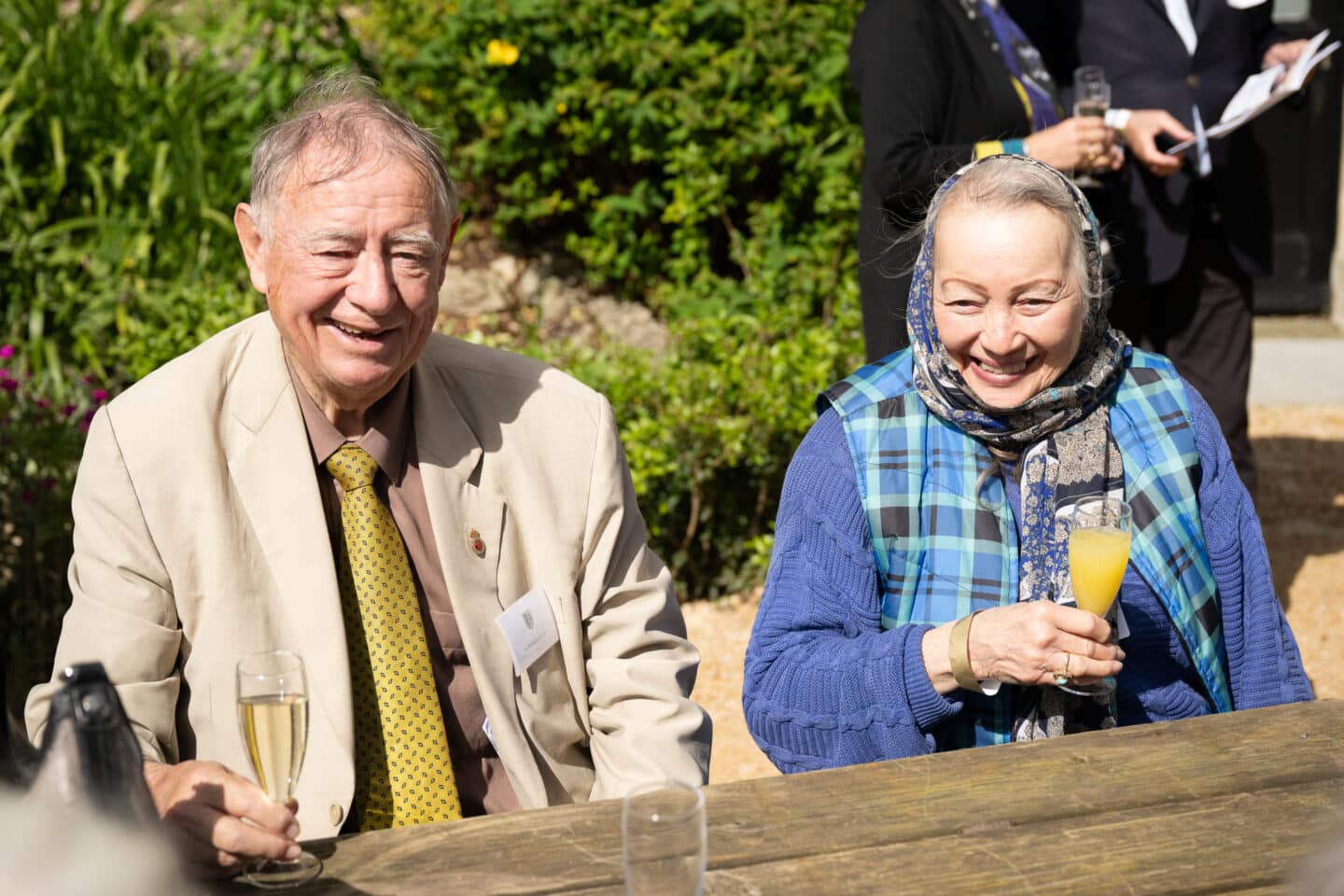 Two people seated at a picnic table with champagne glasses
