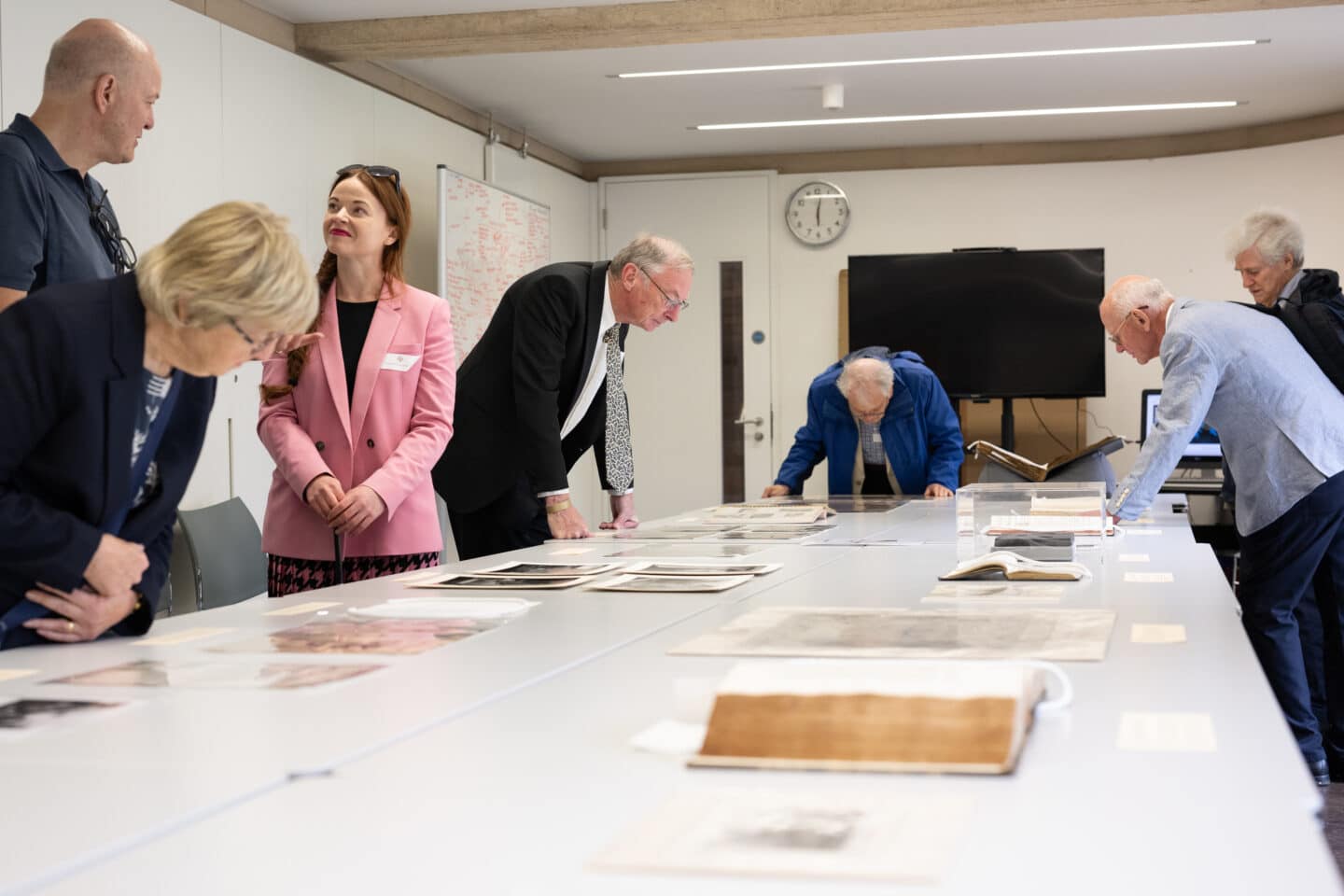 Seven people looking at historical objects laid out on an indoors table