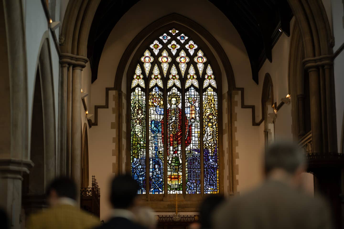 A large stained glass window depicting a man (St Peter) in a robe, holding keys and a chapel, surrounded by other smaller figures