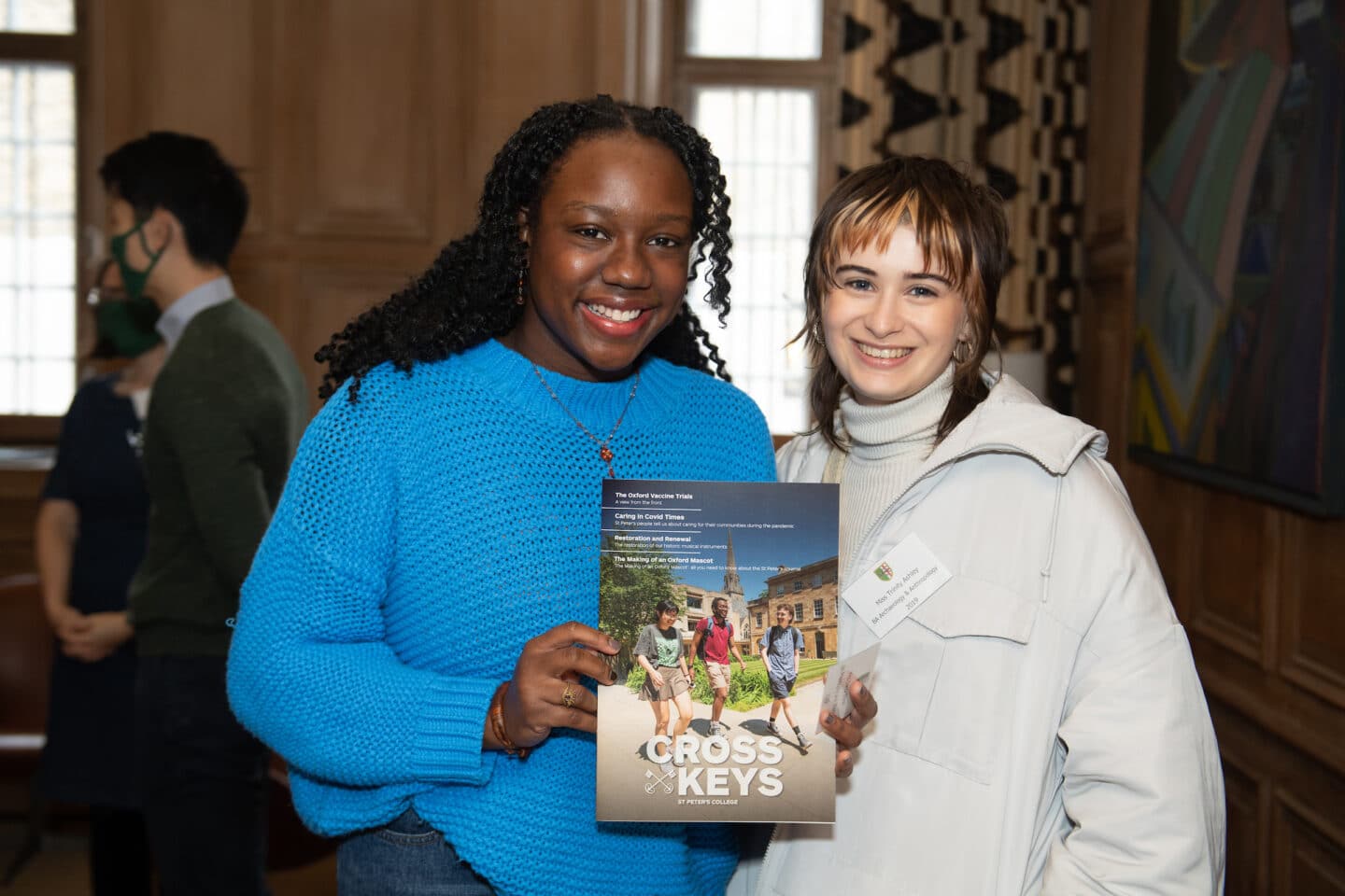 Two people holding an alumni magazine.