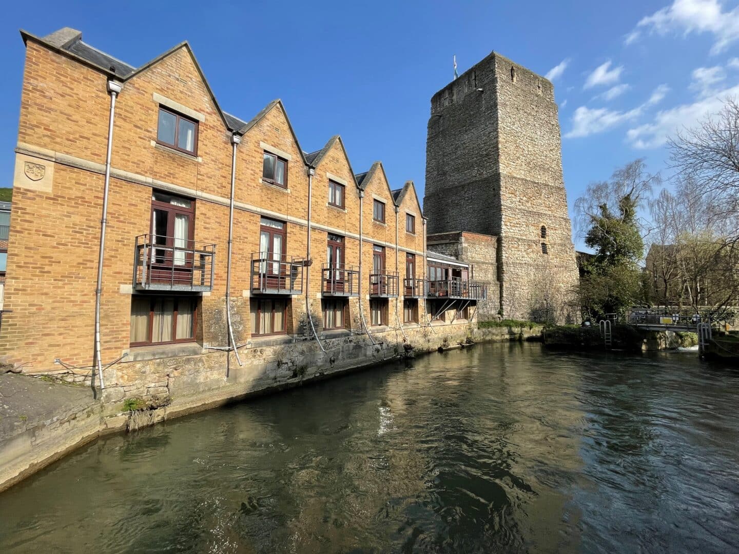 A brick building and old stone tower overlooking a river.