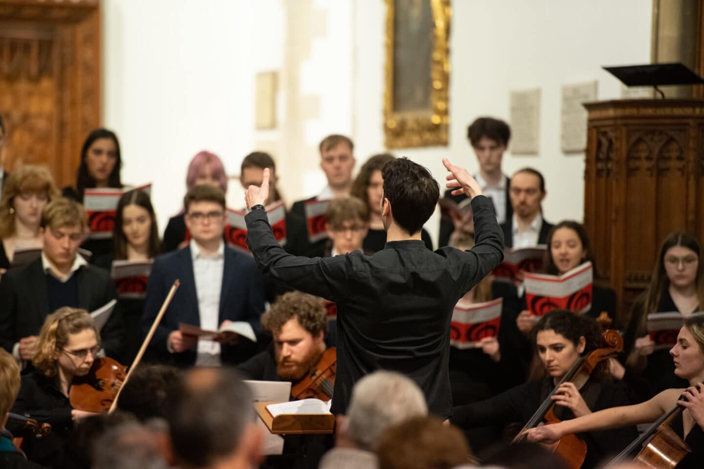 A conductor with orchestra and choir performing in a chapel