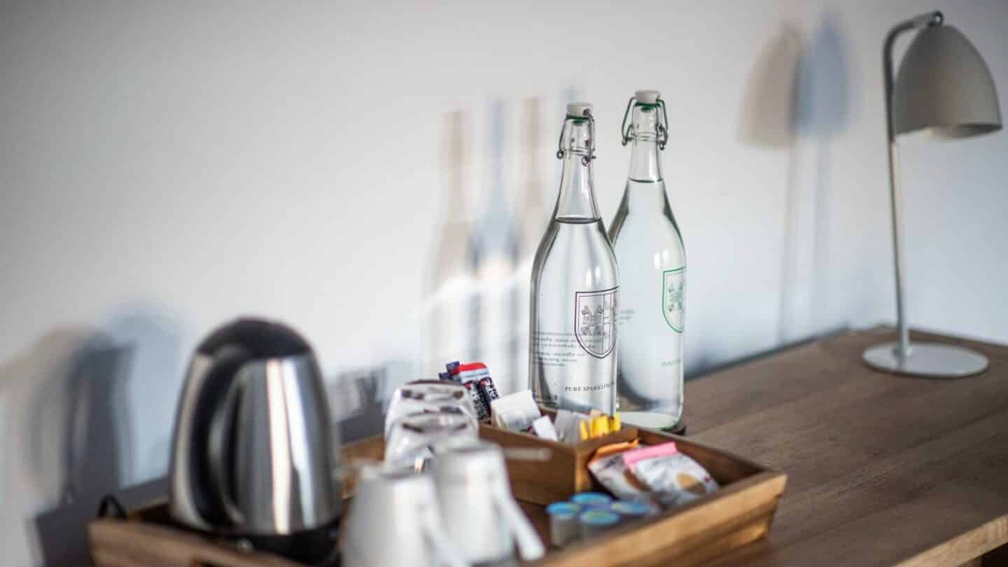 a table with a kettle, mugs and water bottles