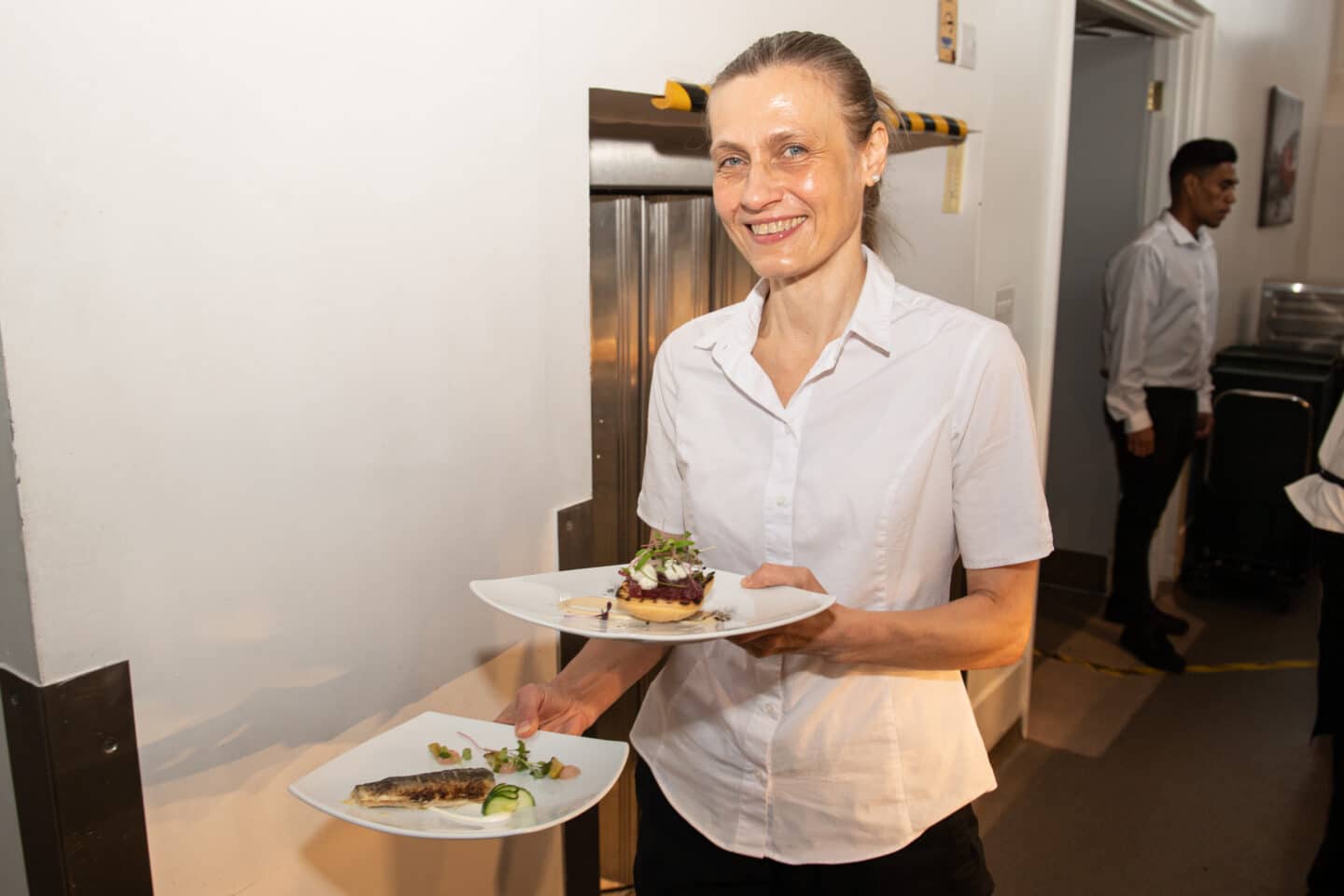 A waiter carrying plated dinners