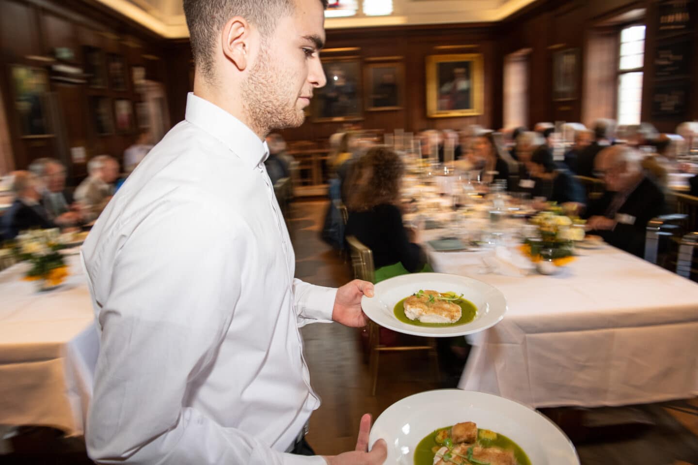 A waiter carrying plated food at a formal luncheon