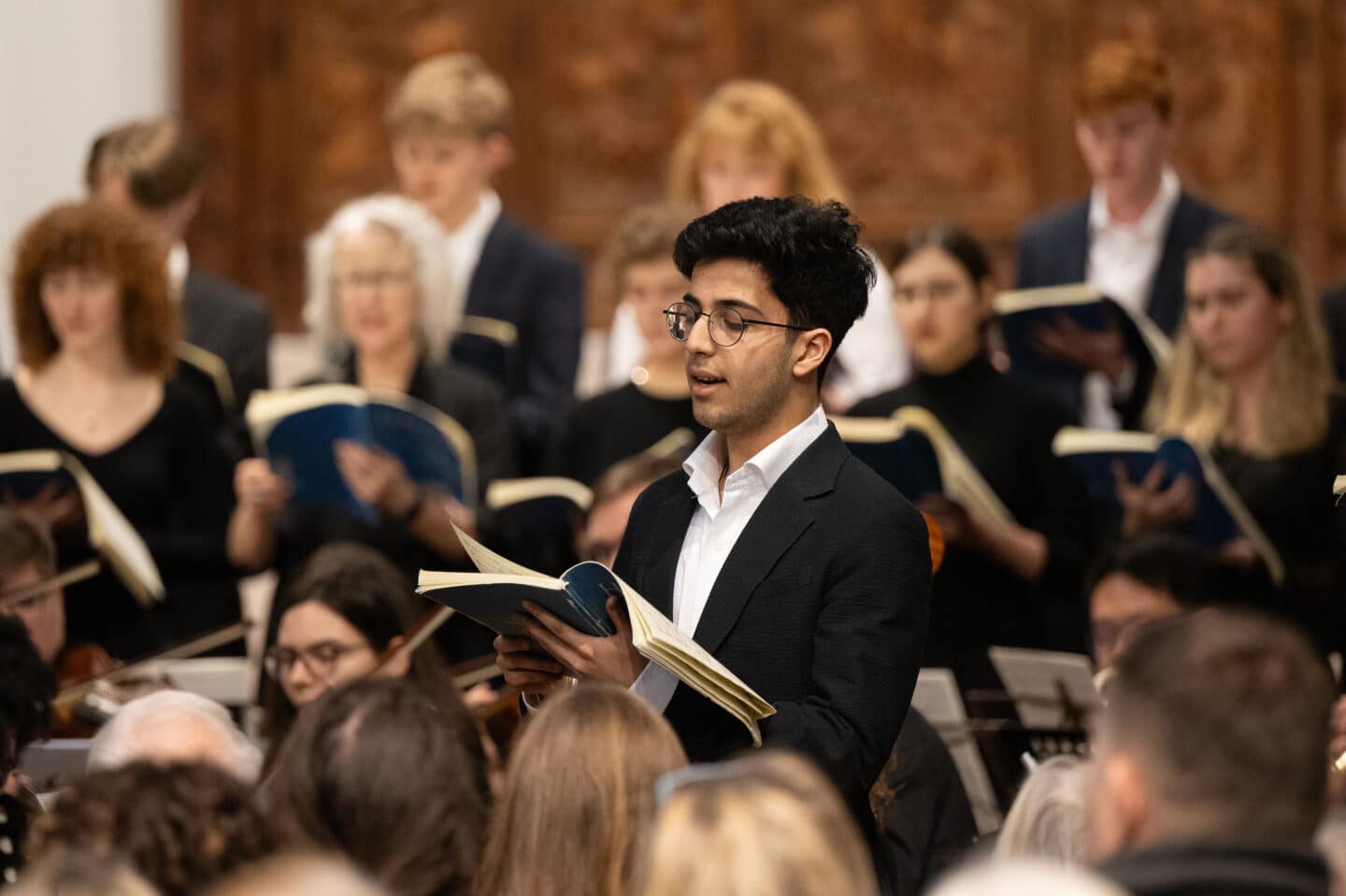 A student singing a solo with a choir in the background