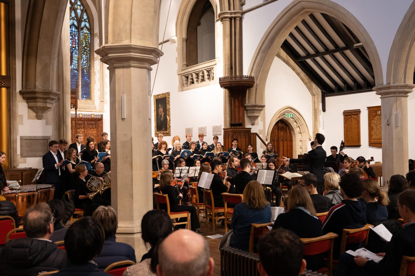 A choir and orchestra performance inside a large and well-lit chapel