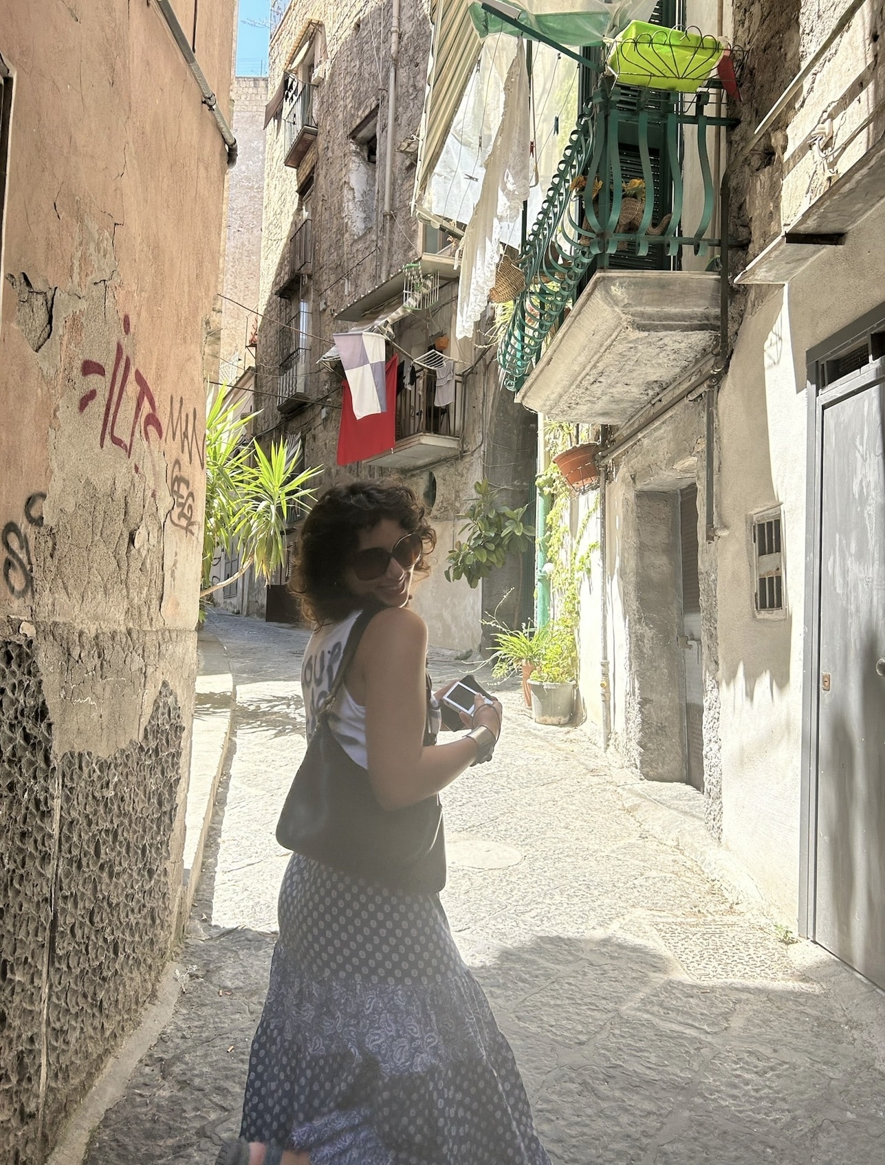 A student walking through a city street, holding a camera