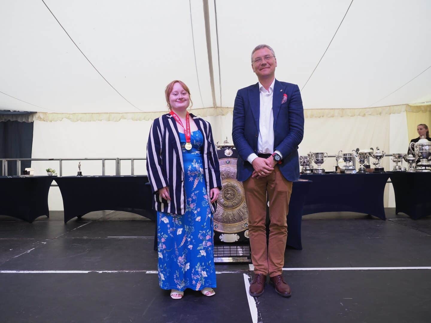 Two people standing on a stage and smiling.