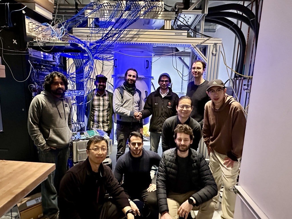 Ten adults in a large computer room area filled with wires.