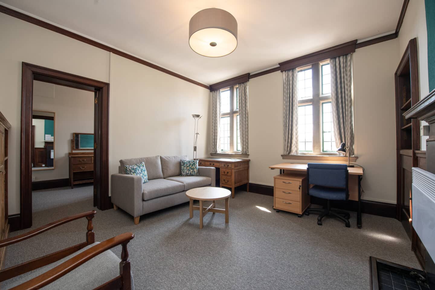 A student room furnished with a sofa, a small table, a desk, and a chair