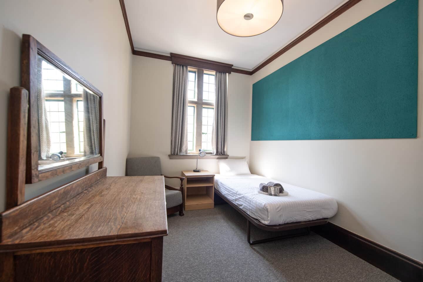 A student room with a bed, a bedside table and chair