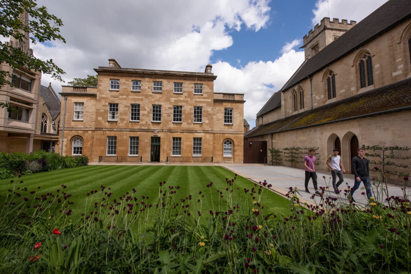 Three people walking through a St Peter's College quad
