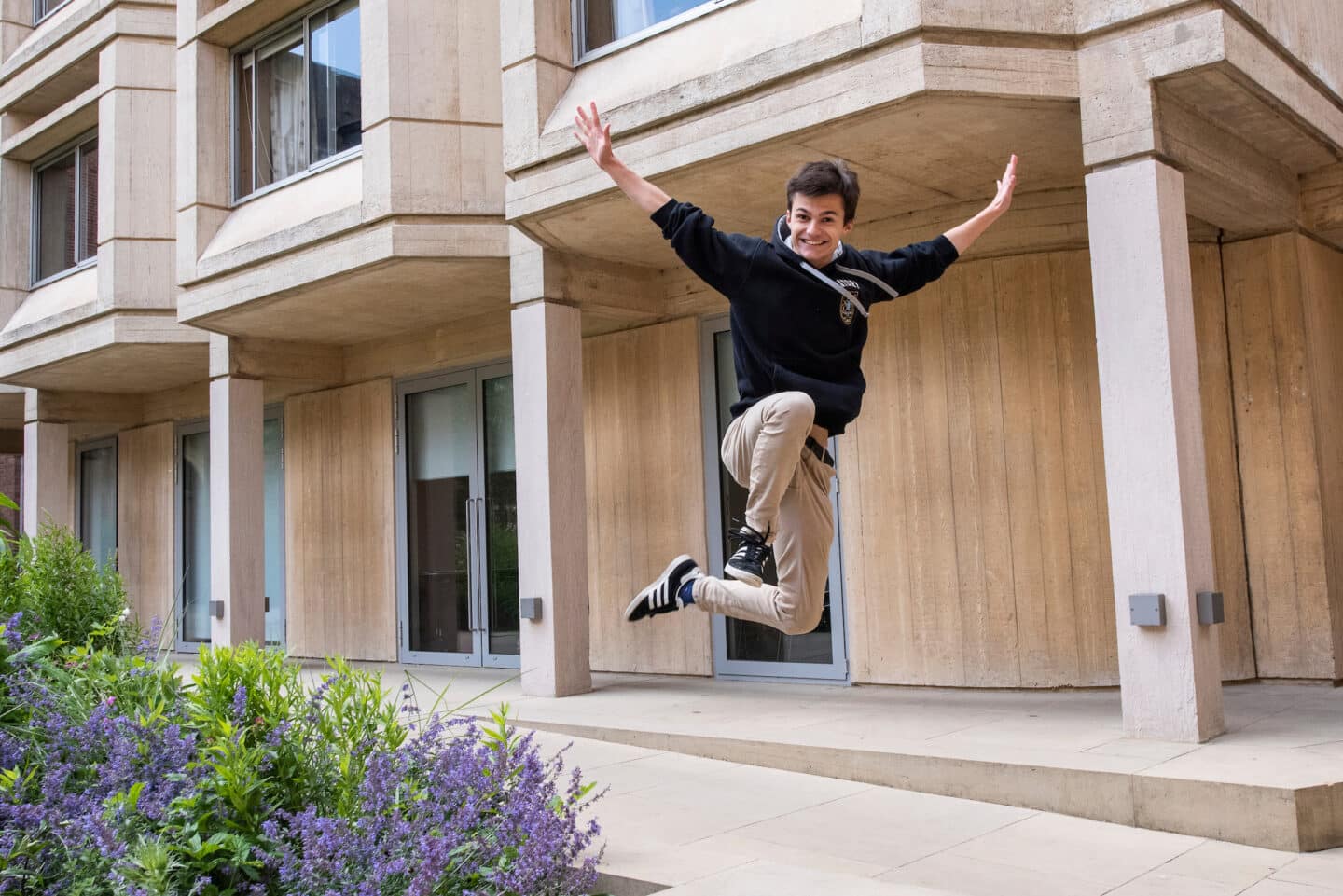 A student smiling and jumping in the air