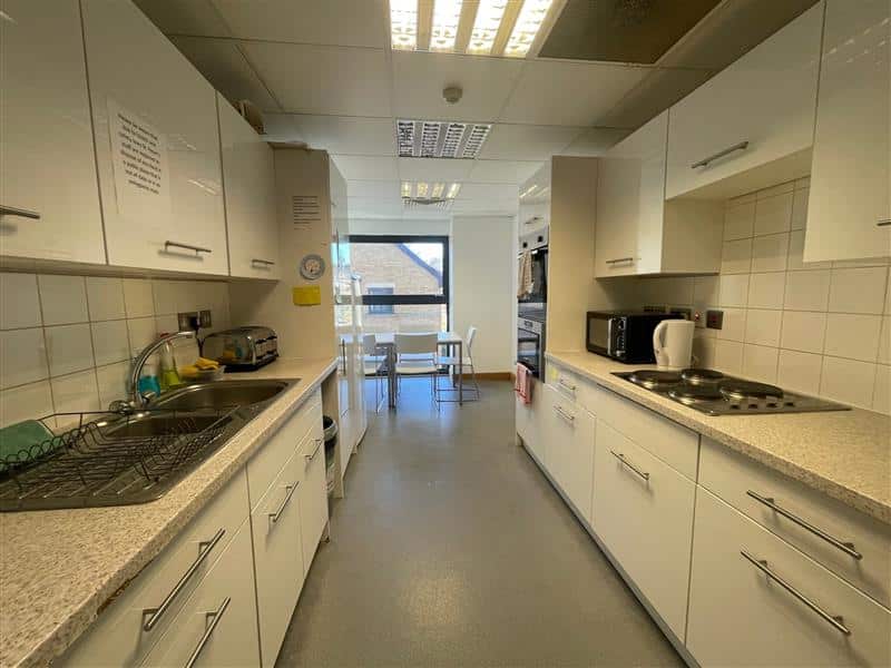 Kitchen with sink, hob, cupboards and a table and chairs