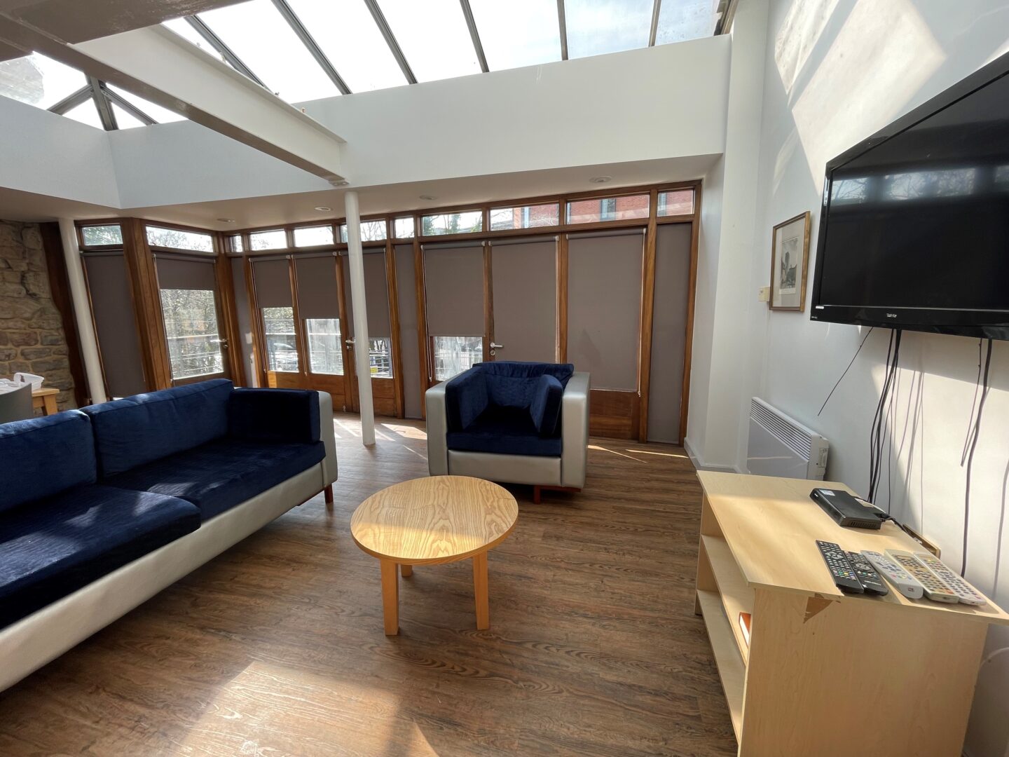 A spacious and well-lit sitting room with a sofa, table, and television