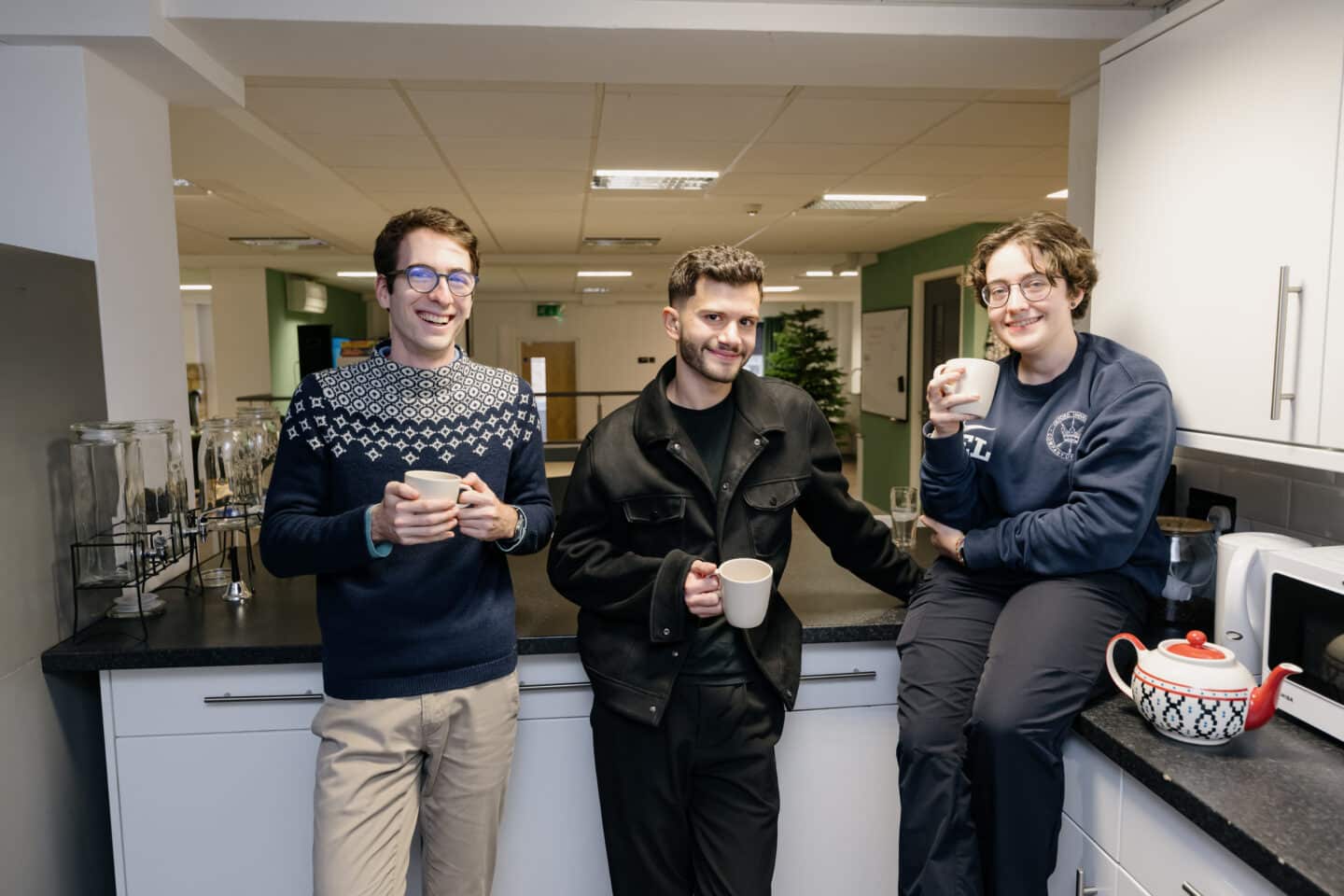 three people holding mugs and smiling