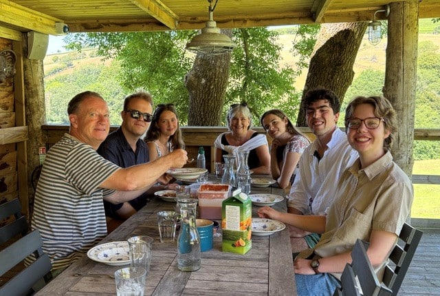 a group of students and adults sat at a table on a patio or porch