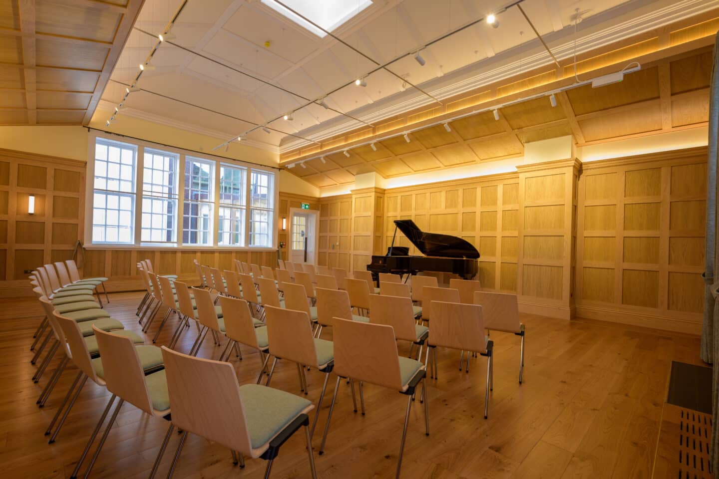 a wood-panelled room with several chairs and a piano