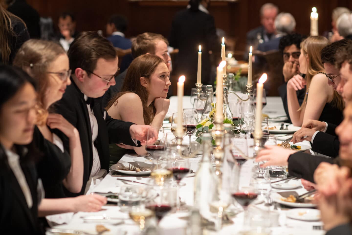 Group of guests during Formal dinner, sat at a dressed table with candles.