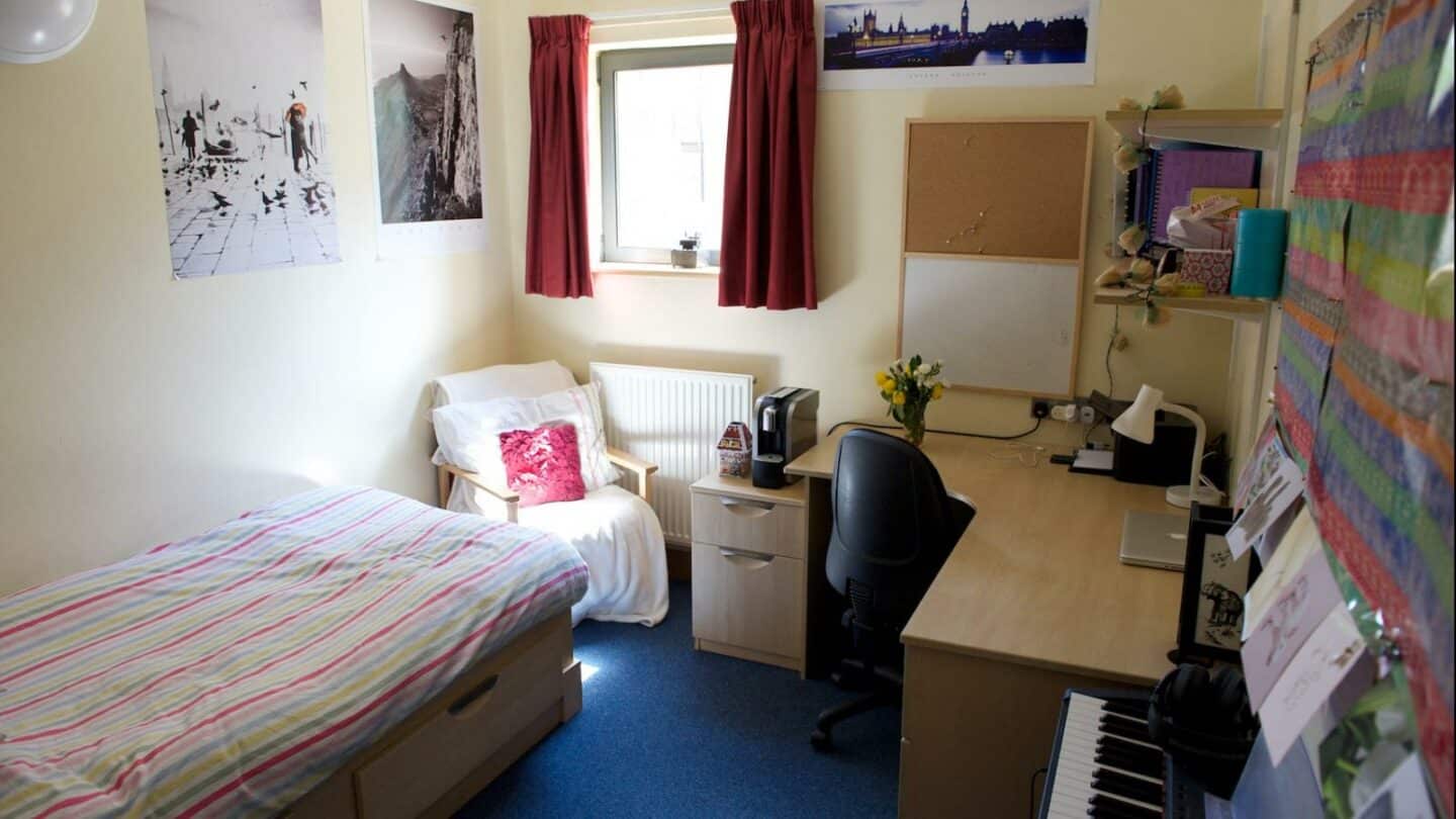 A student room with a desk, chair and bed