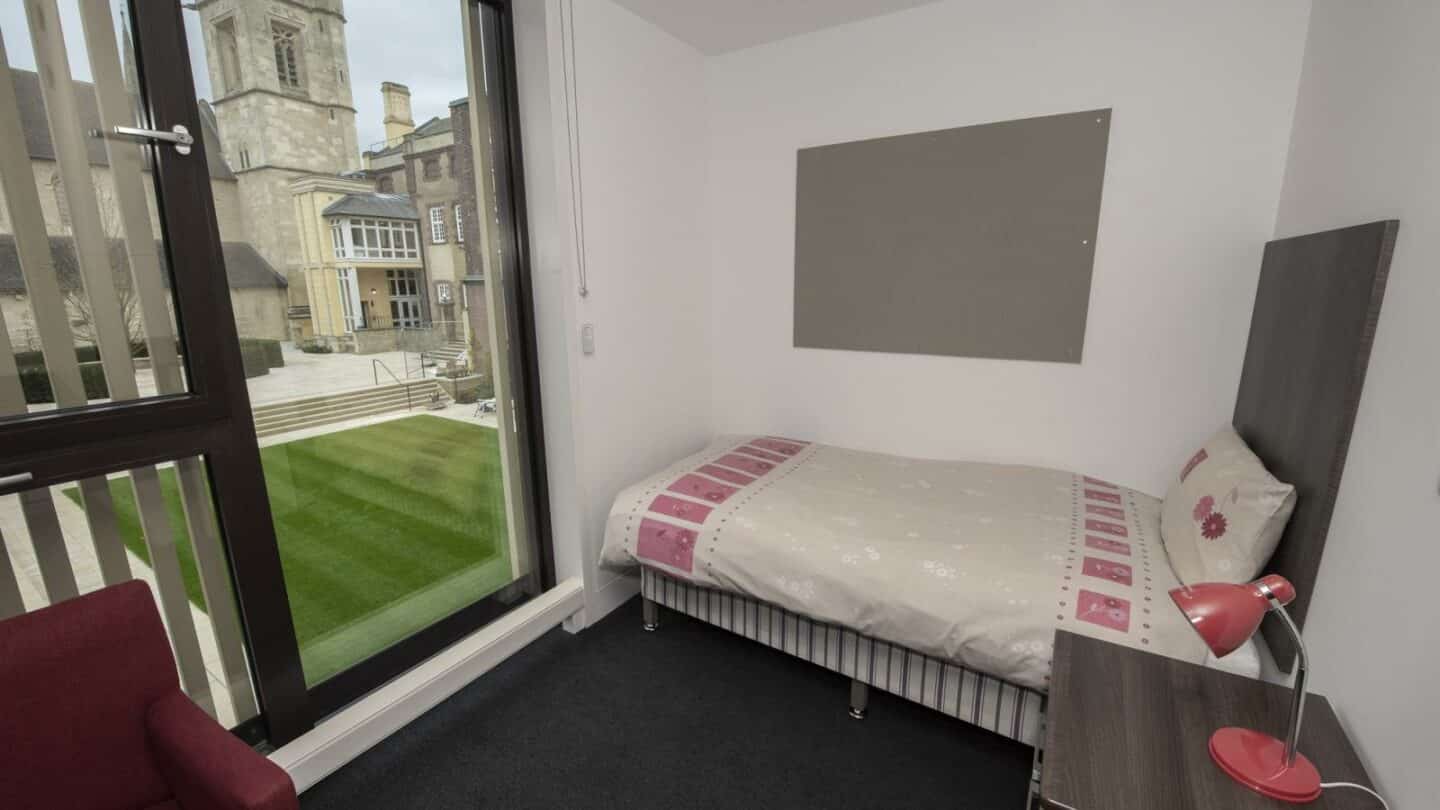 A room with a chair, bed and bureau