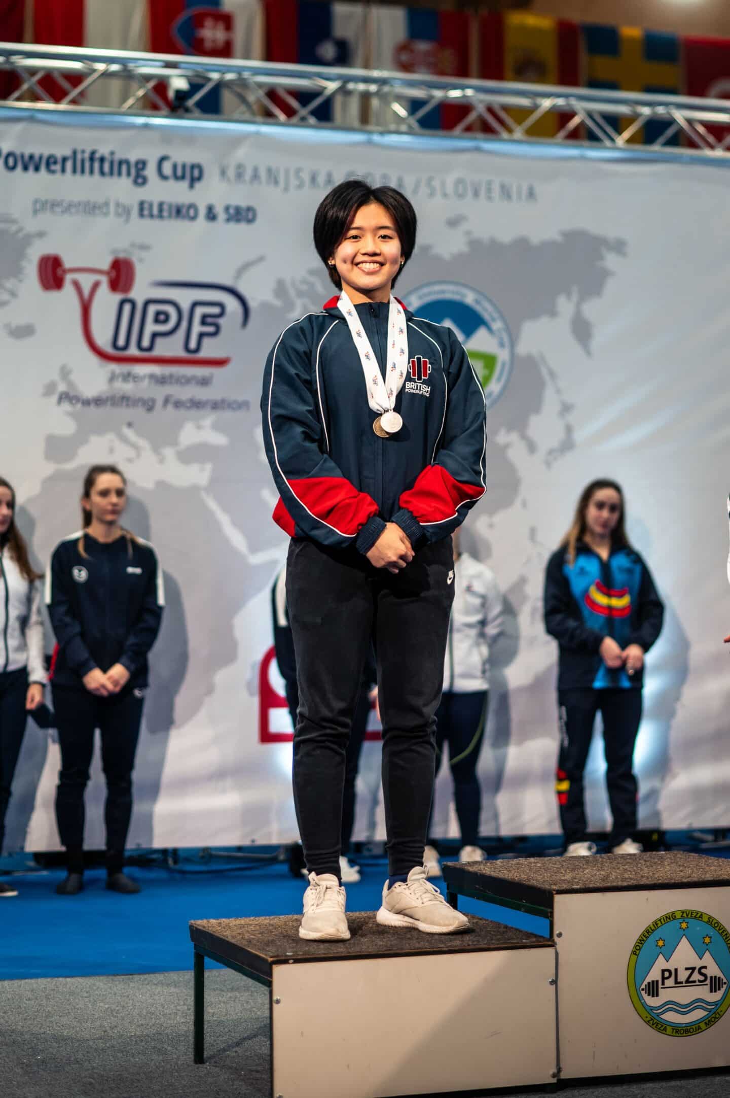 A woman wearing a tracksuit and medals at a sporting ceremony