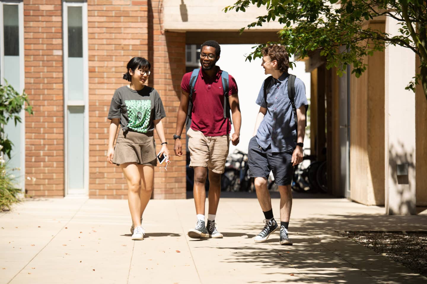 three students walking in a quad