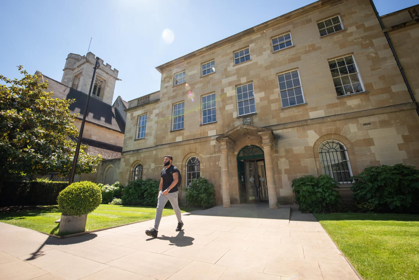 A student walking outside of the St Peter's College Porters' Lodge