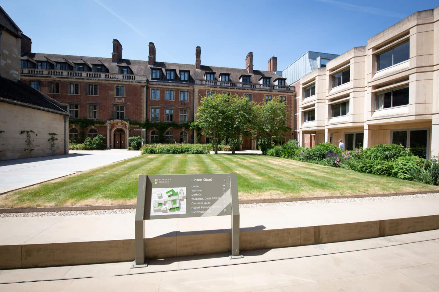 Brick and concrete buildings surrounding a green lawn in the sun