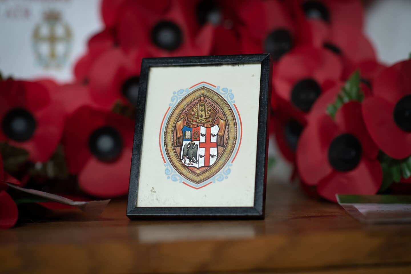 A framed coat of arms with a backdrop of poppy wreaths.