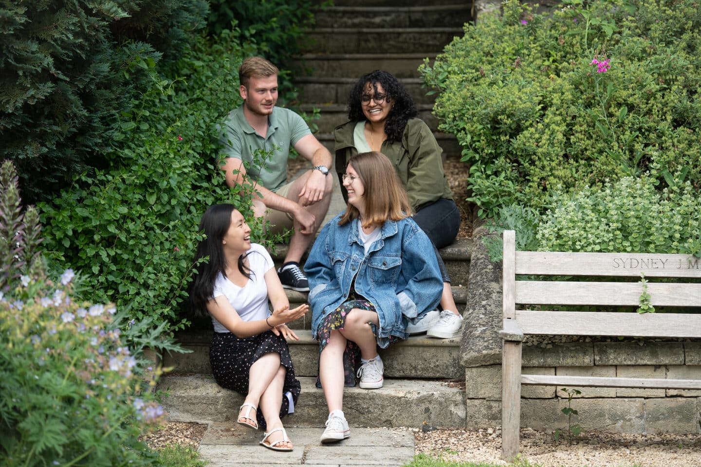 Four students smiling and chatting in a garden