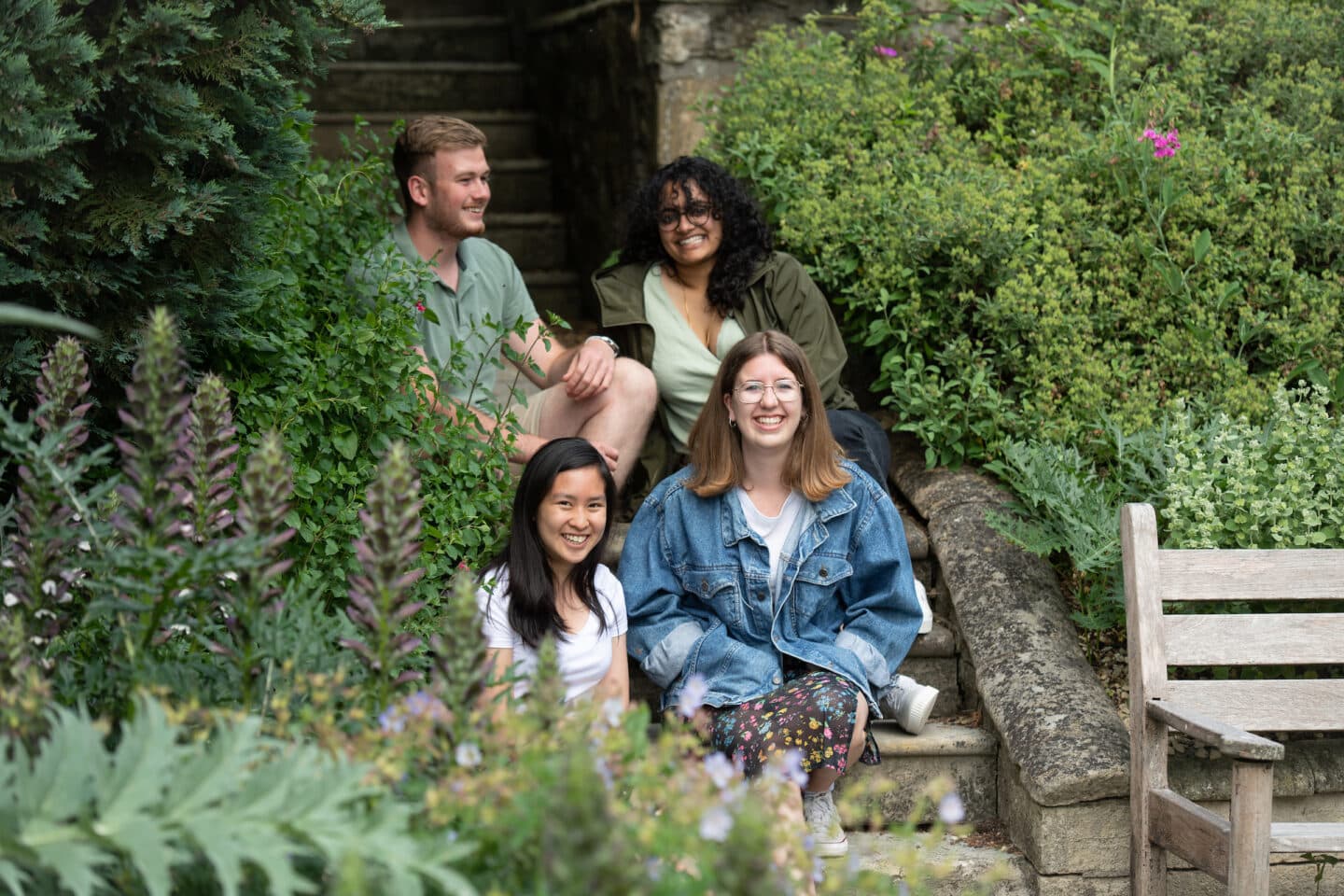 A group of four students sitting in a garden and smiling