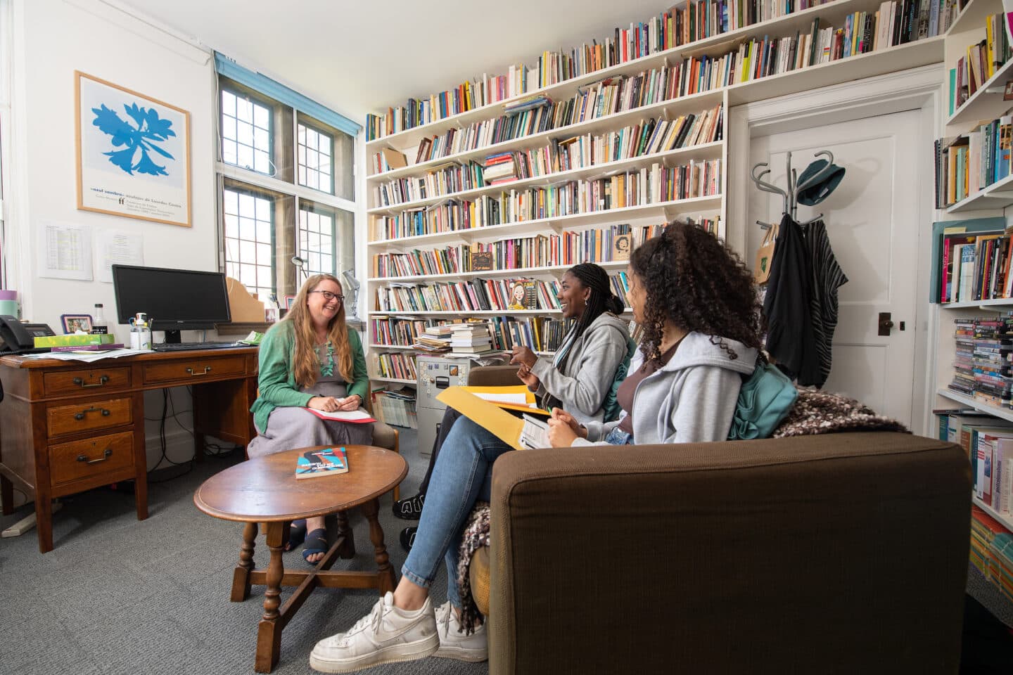 A tutor and two students in an office filled with books