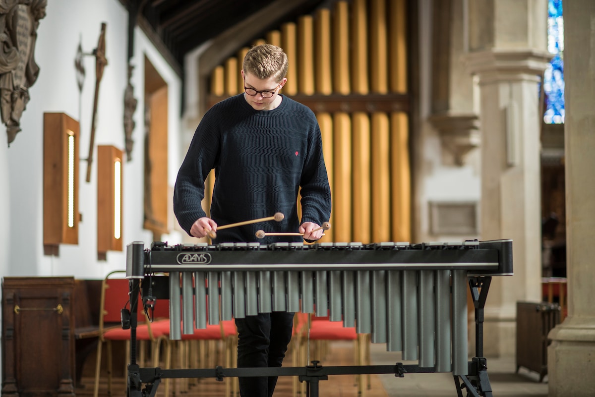 A person playing a xylophone in a large stone building