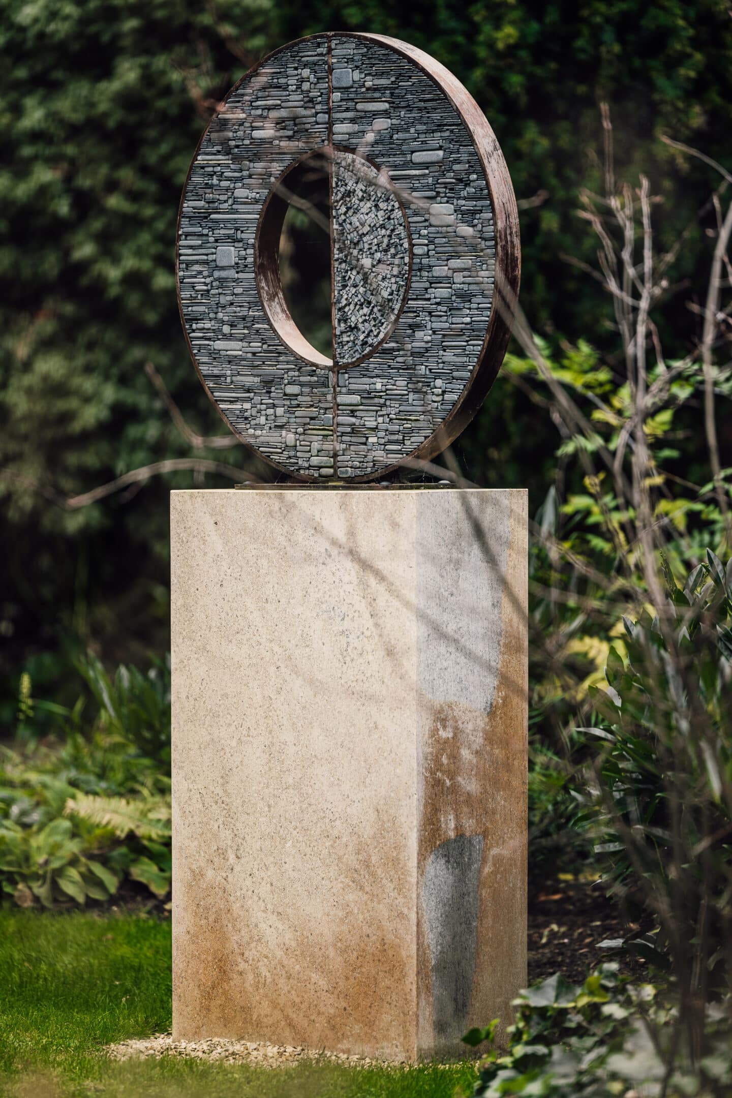 An abstract sculpture made of small pieces of stone fit into a bronze circle